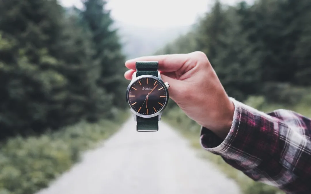 person holding round black analog watch